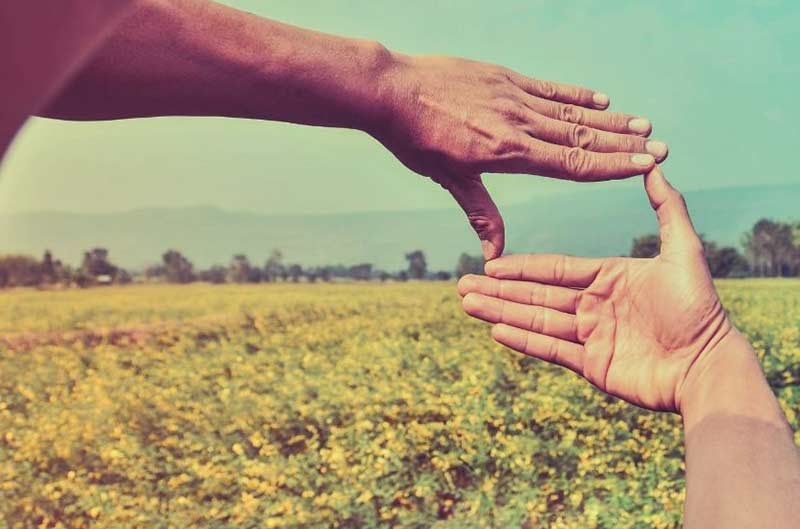 two hands making a frame in front of landscape scenery