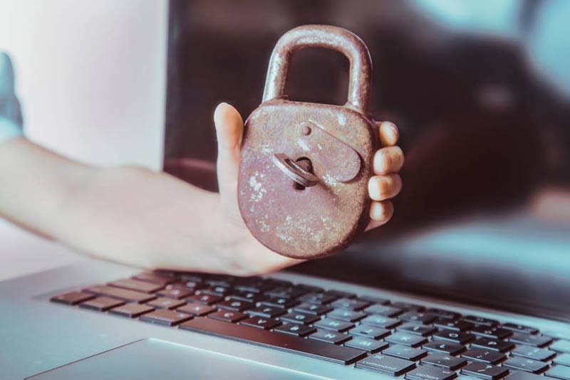 rusty padlock and key being help over a laptop