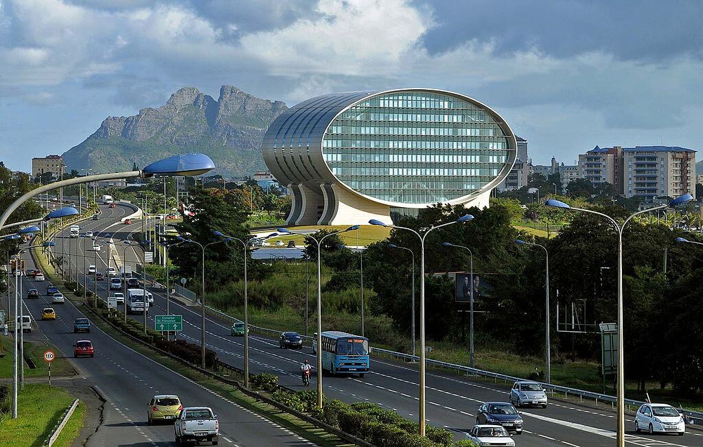 Mauritius Commercial Bank building in Ebene, viewed from highway with cityscape and mountain backdrop.