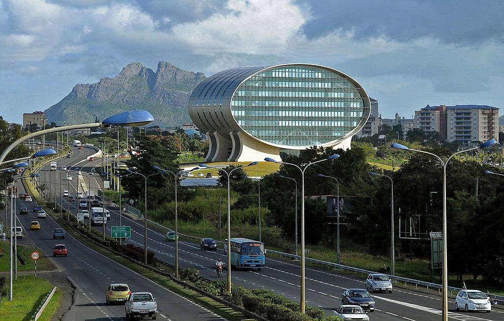 Mauritius Commercial Bank building in Ebene, viewed from highway with cityscape and mountain backdrop.