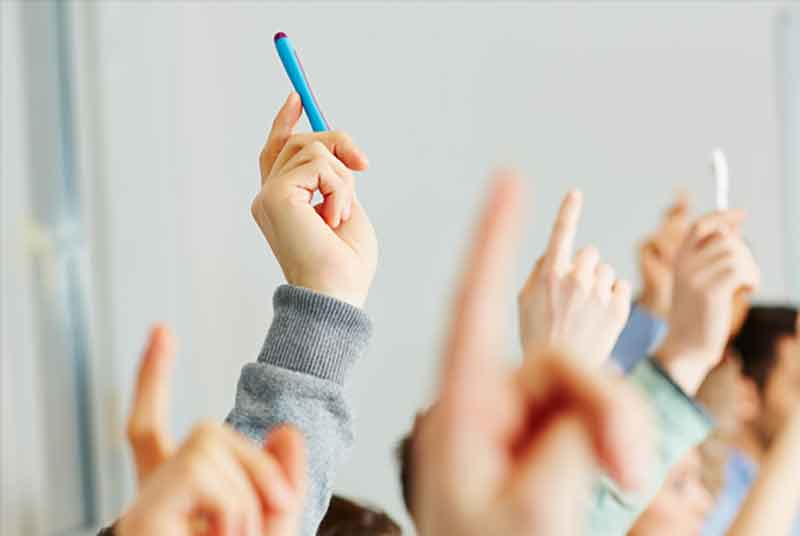 pupils raising their hands in a class
