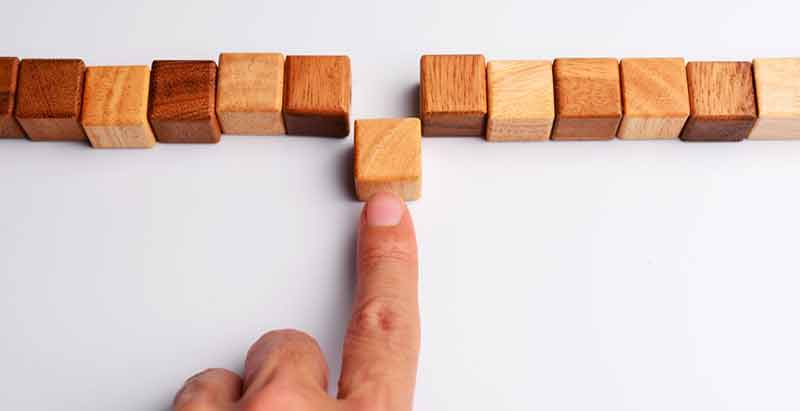 row of twelve wooden blocks with someone separating one from the row