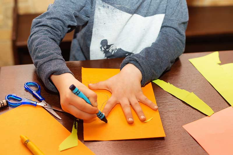 a child with a crayon drawing around their hand